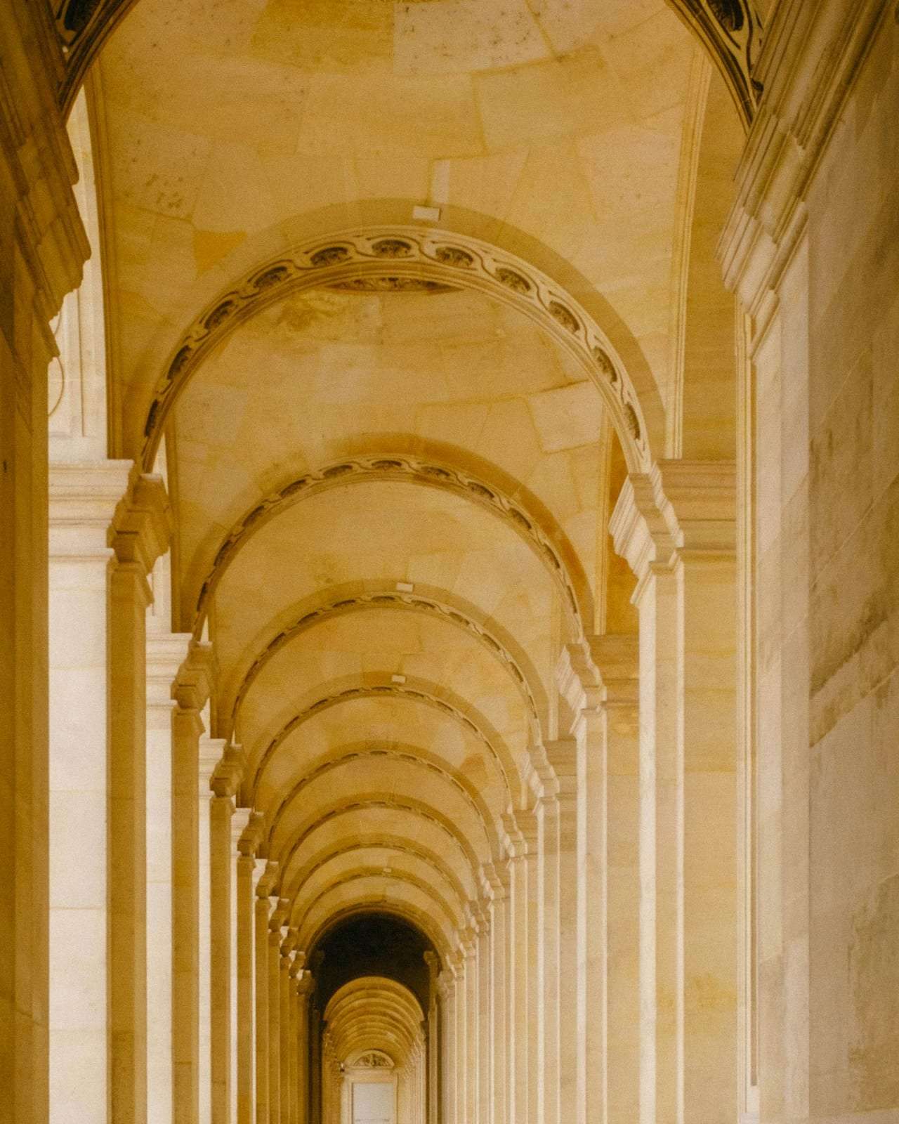 A stone colonnade with vaulted arches receding into warm light