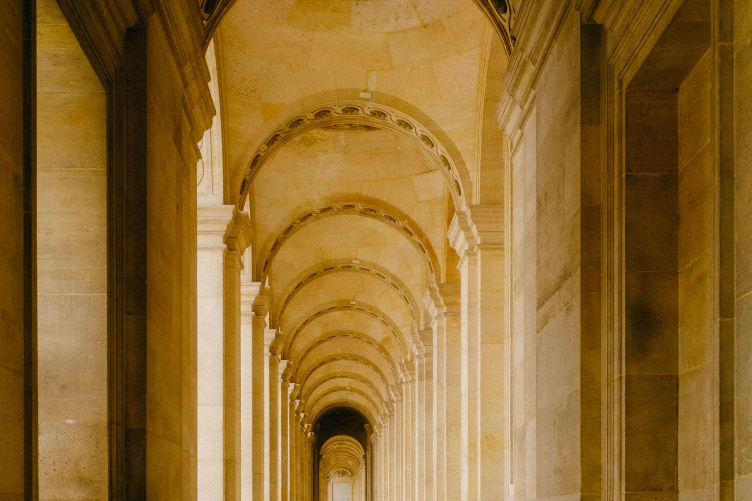 A stone colonnade with vaulted arches receding into warm light