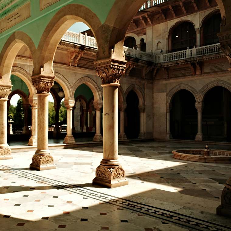 A courtyard of stone arches, sunlight crossing the tiled floor