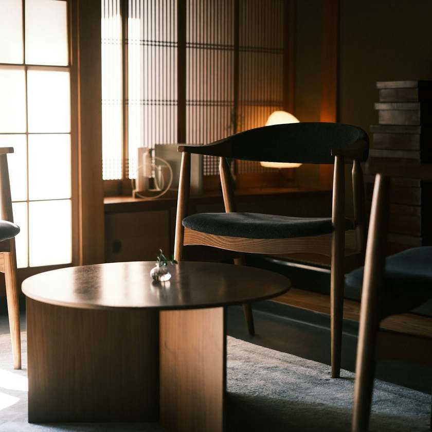 Two wooden chairs at a round table in soft light from a paper screen