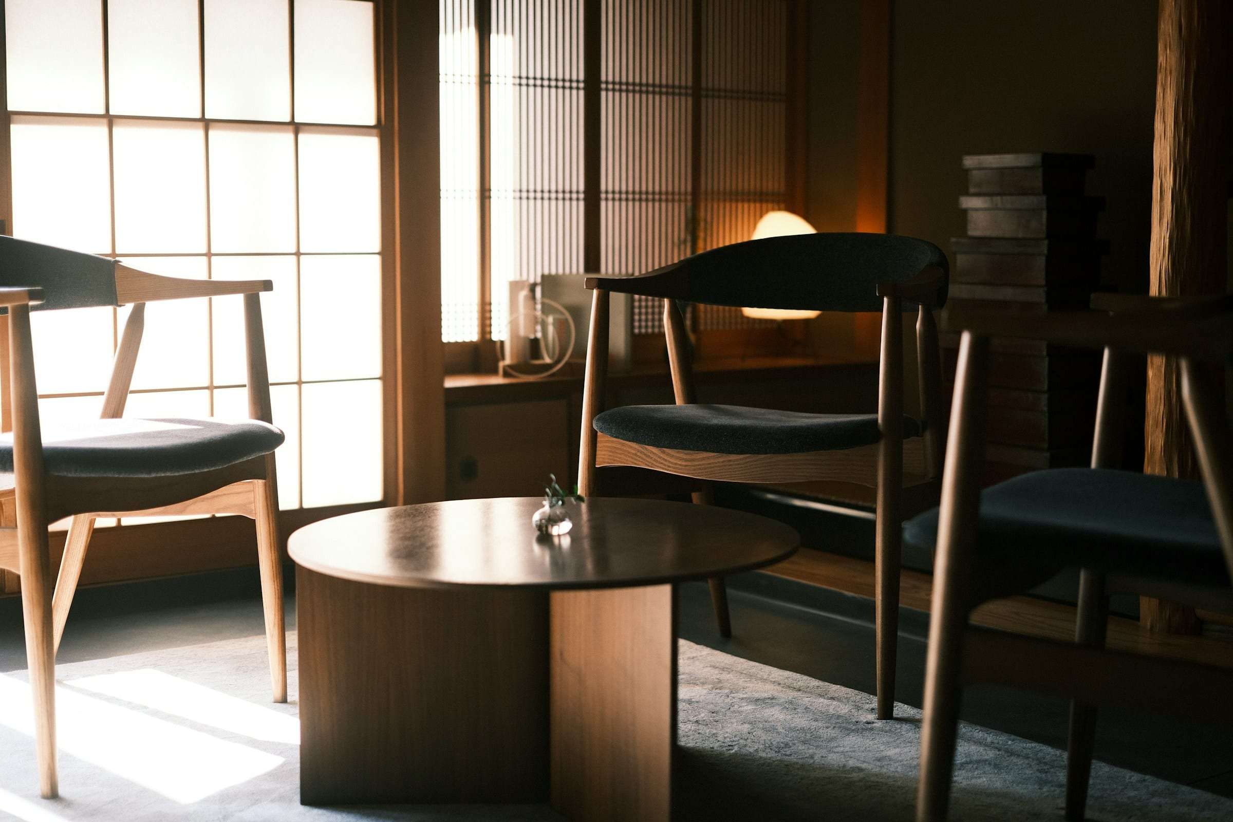 Two wooden chairs at a round table in soft light from a paper screen