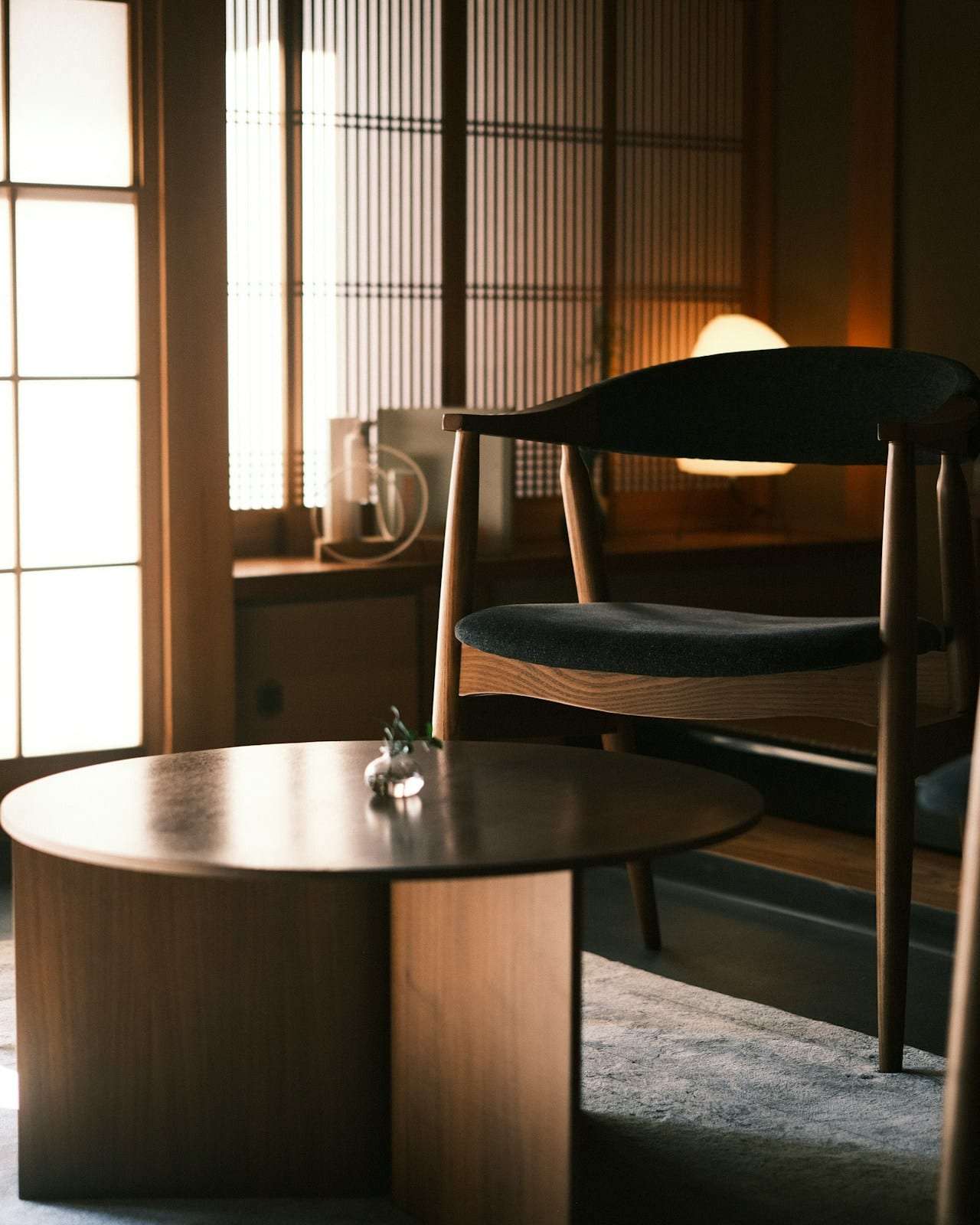 Two wooden chairs at a round table in soft light from a paper screen