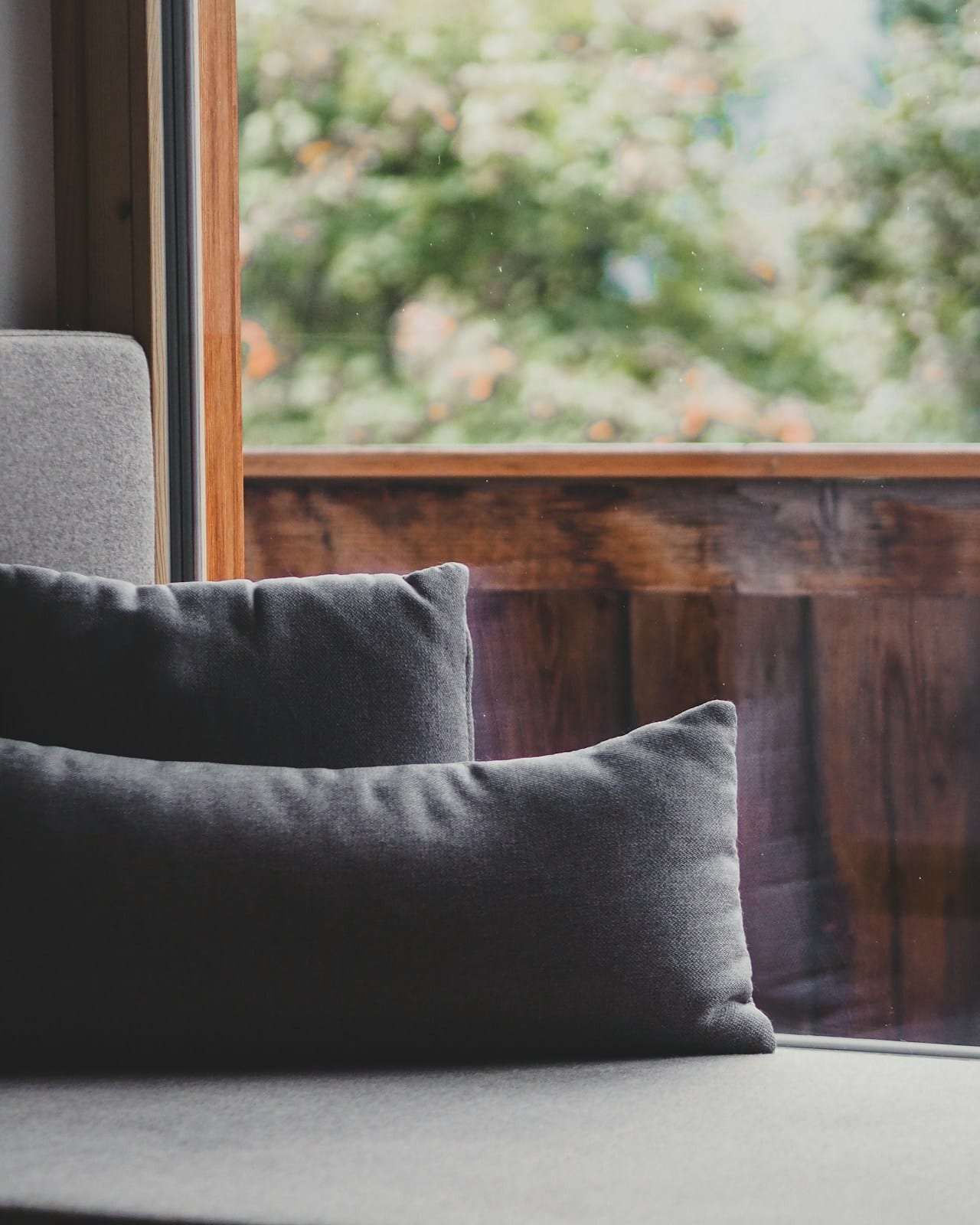 A window seat with cushions looking onto a wooden balcony