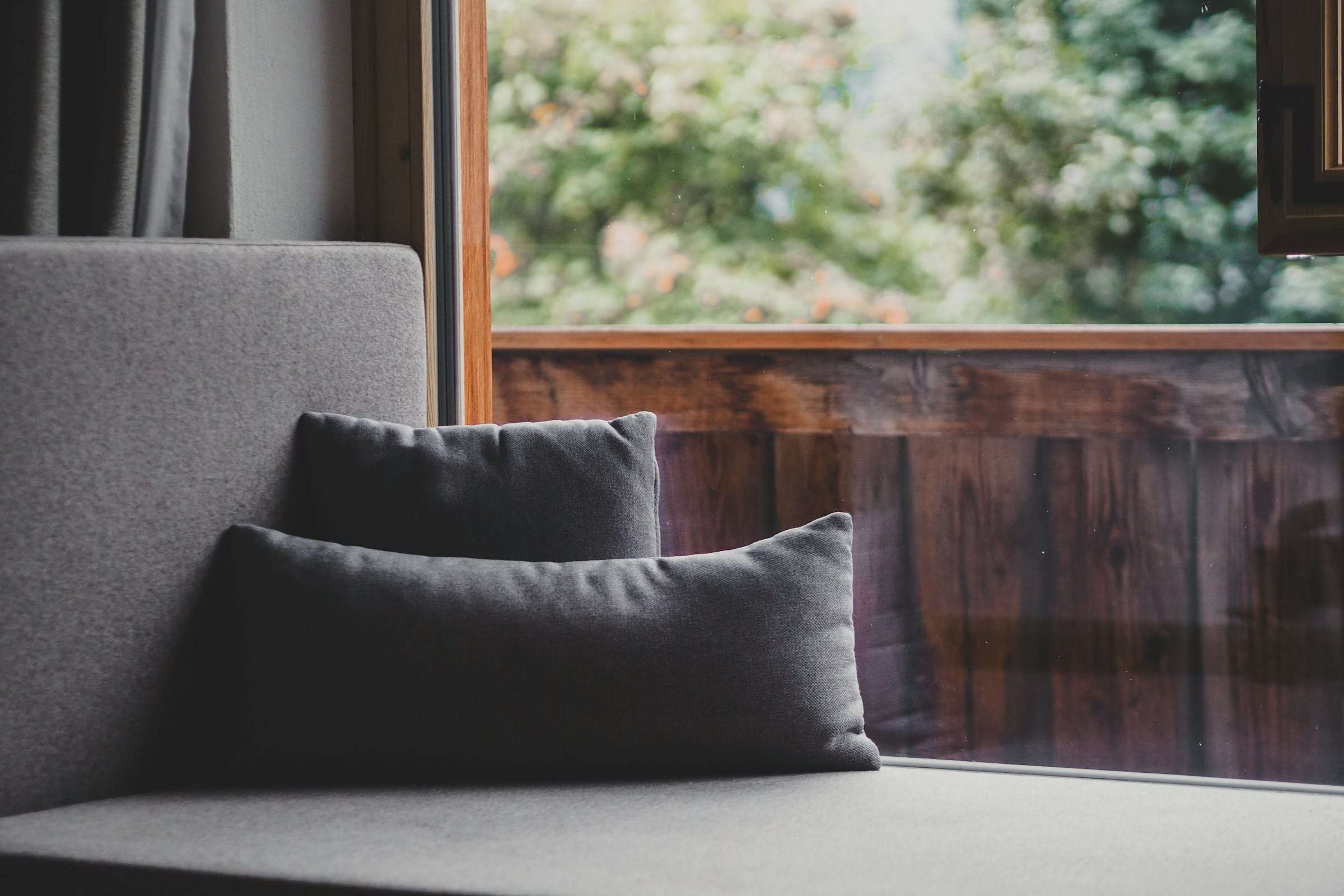A window seat with cushions looking onto a wooden balcony