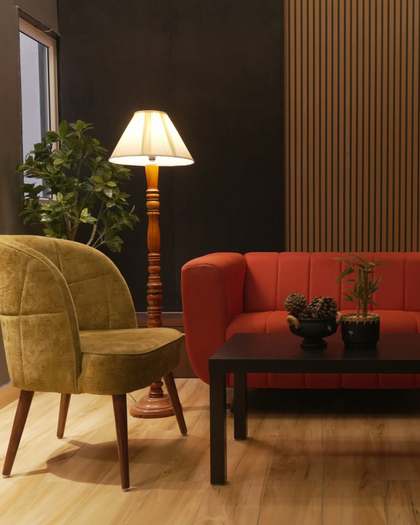 A lamplit lounge with an armchair and sofa facing a low table