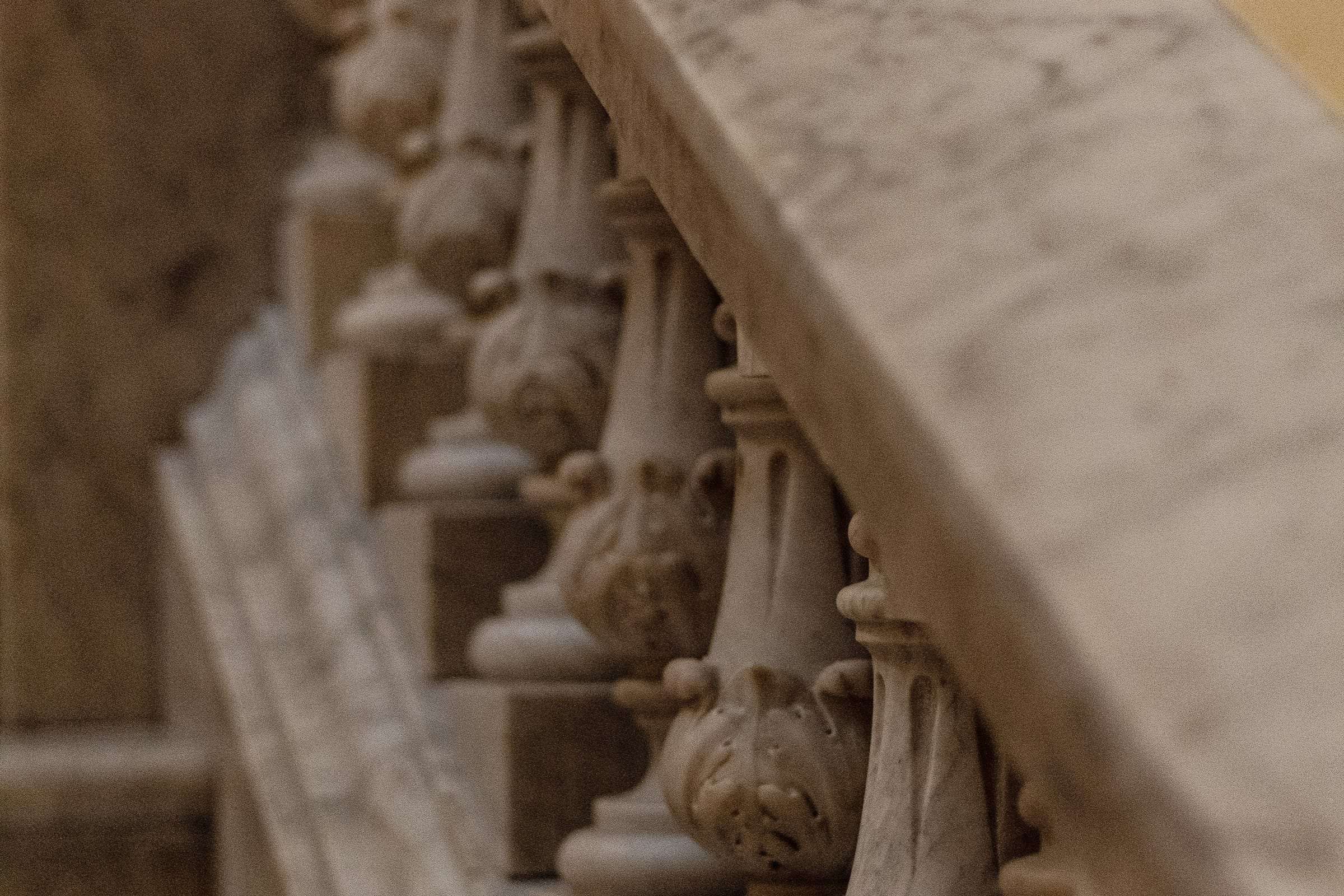 A marble staircase with a curving balustrade, seen rising toward the light