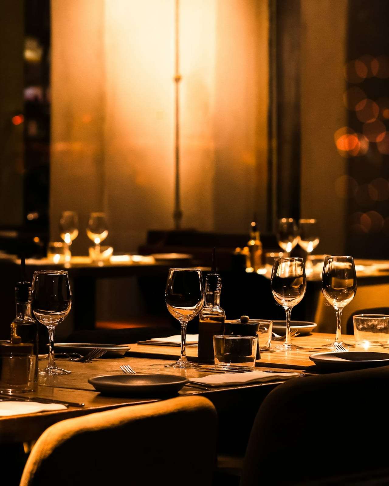 A dark restaurant with tables set and no guests yet