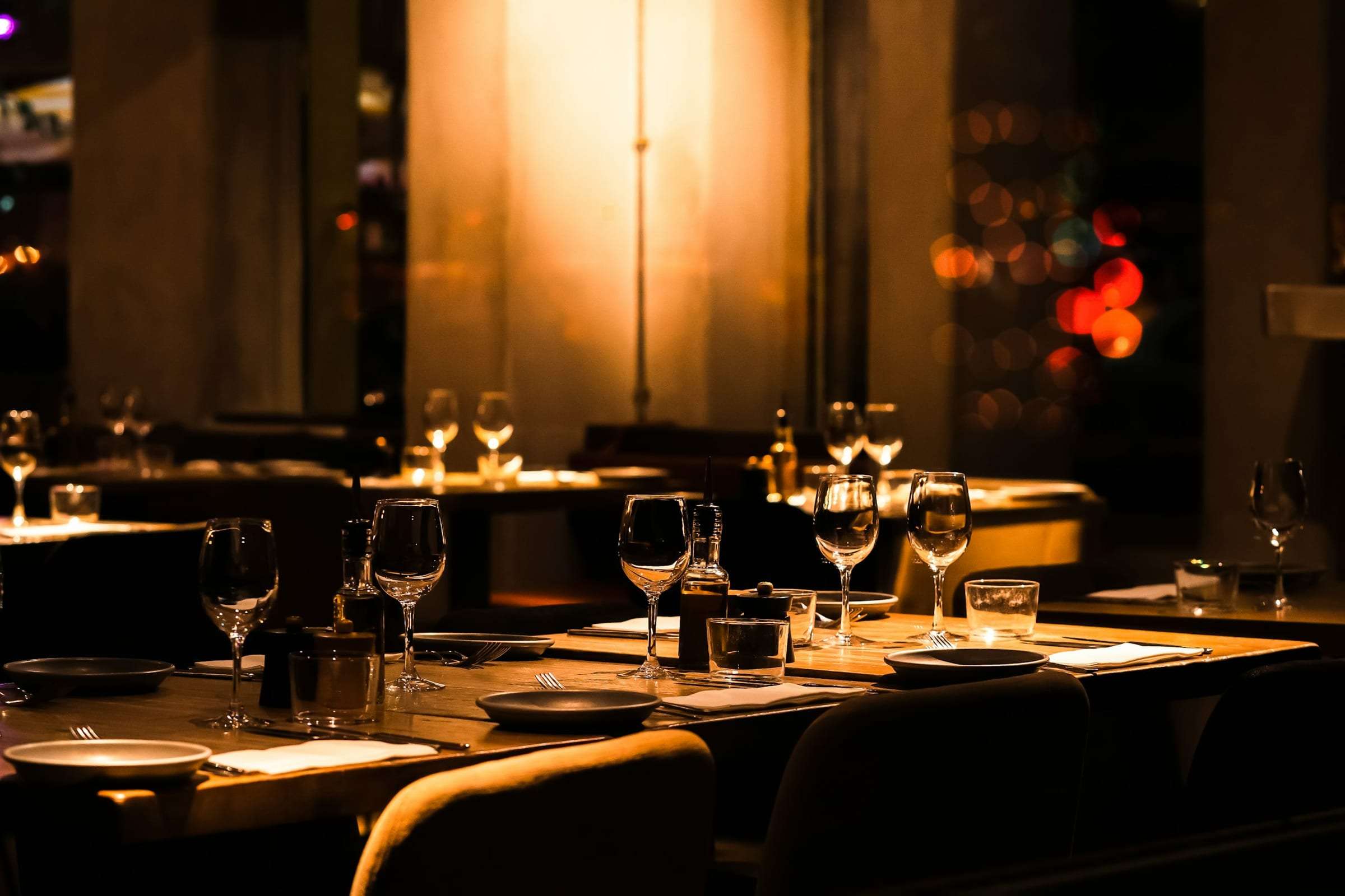 A dark restaurant with tables set and no guests yet
