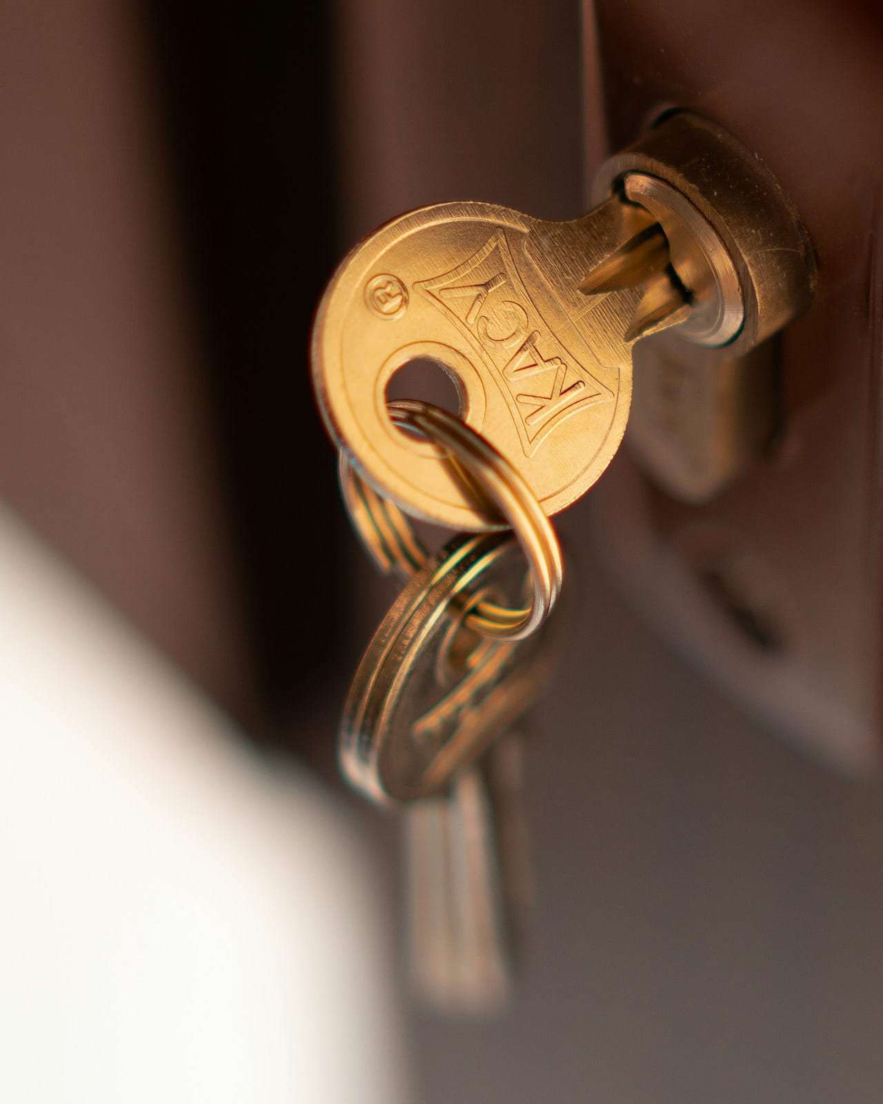 A brass key resting in the lock of a dark wooden door