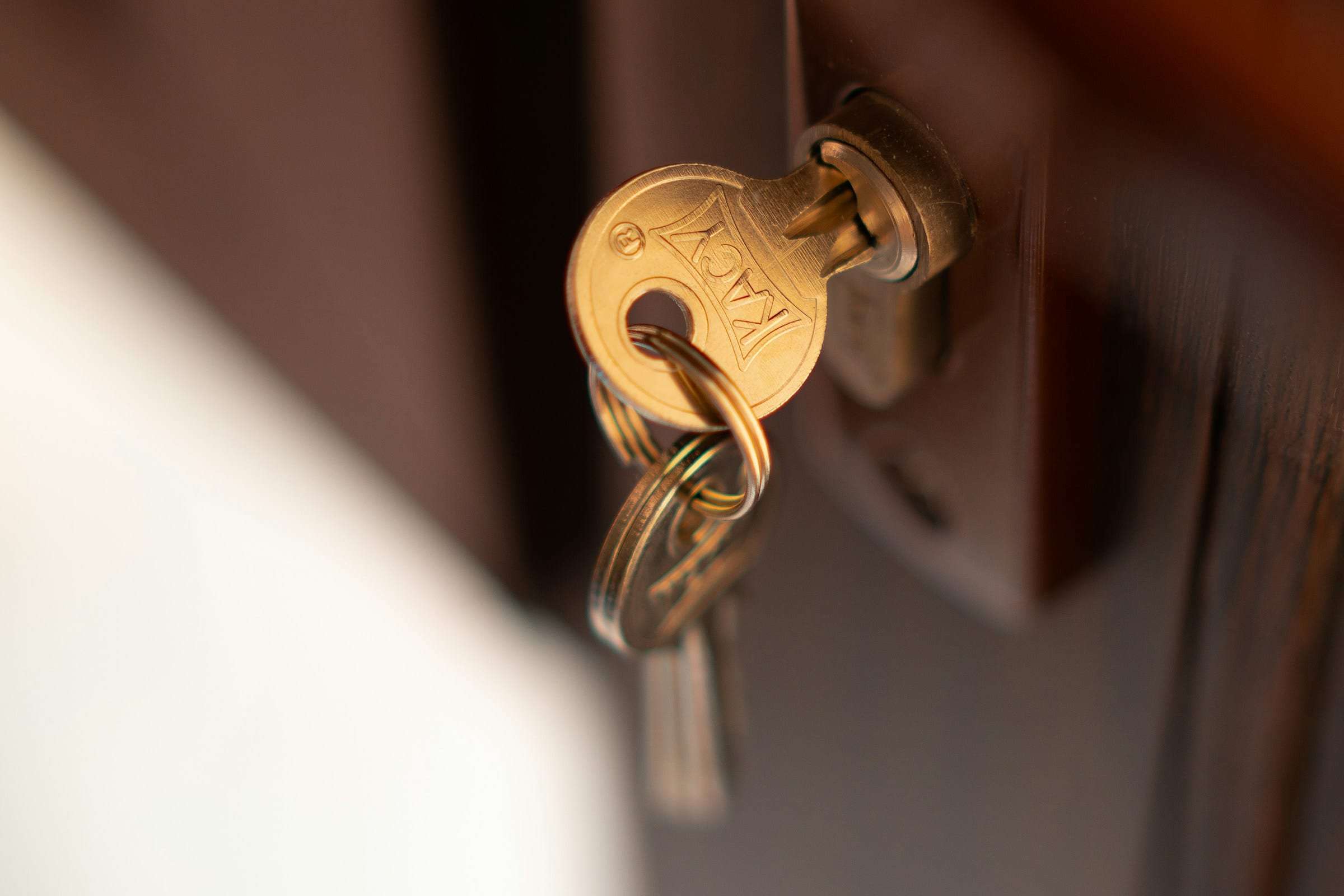 A brass key resting in the lock of a dark wooden door
