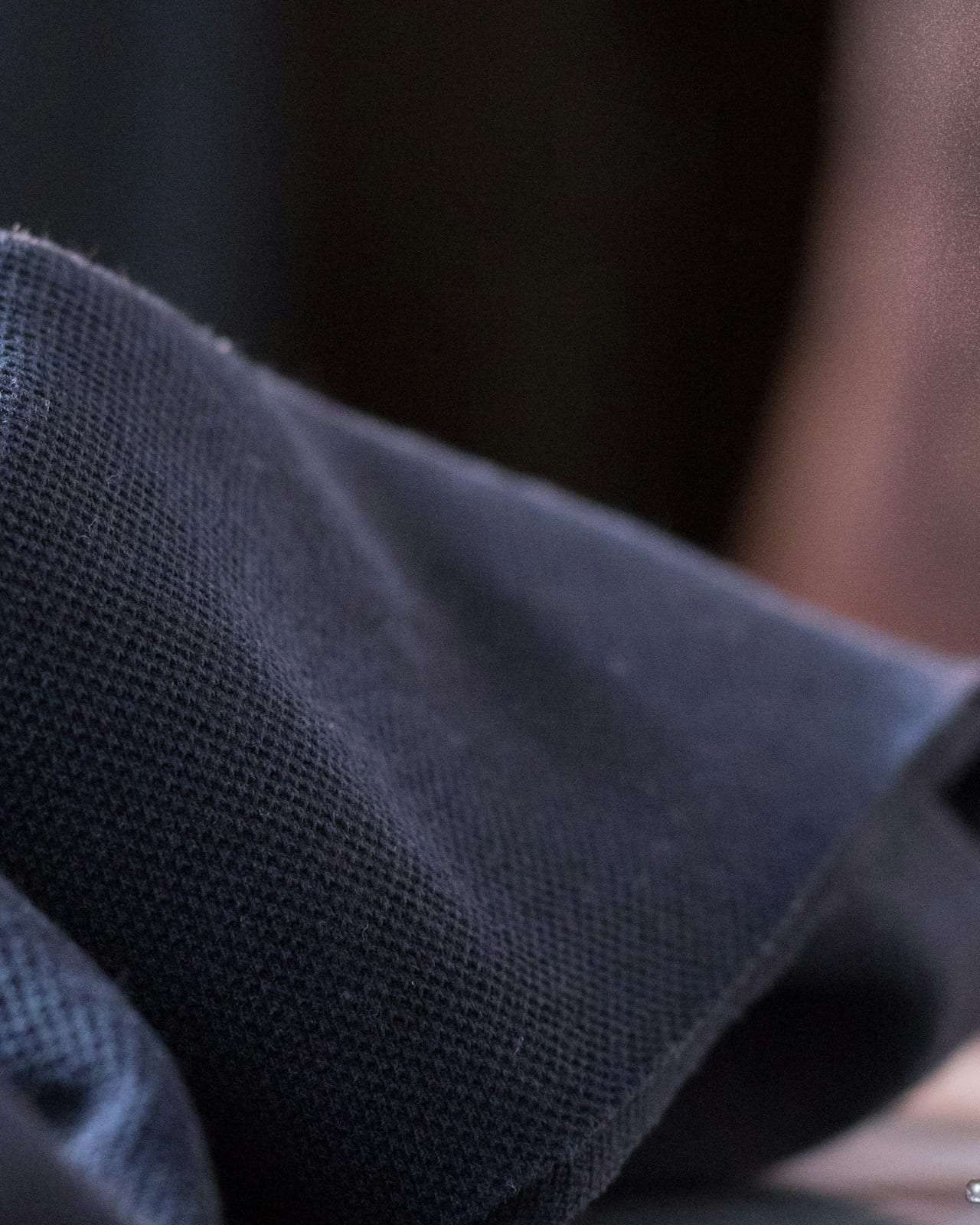 Navy wool cloth beneath the foot of a tailor’s sewing machine